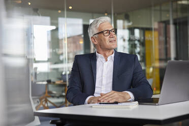 Thoughtful male professional looking away while sitting in office - RBF08183