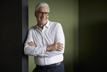 Mature male professional with arms crossed leaning on wall - RBF08192