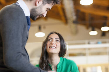 Smiling male and female professionals looking at each other in office - EIF00947