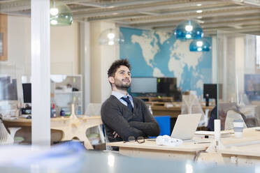 Male professional contemplating while sitting in front of laptop at office - EIF00952