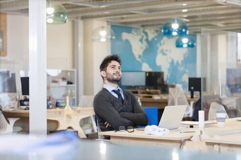 Männlicher Berufstätiger, der vor einem Laptop im Büro sitzt und nachdenkt - EIF00952