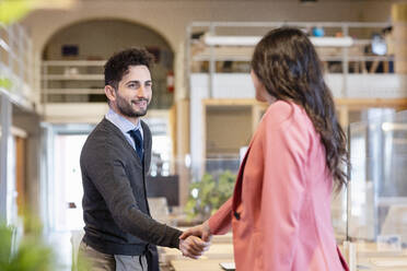 Junger Geschäftsmann schüttelt Hände mit Unternehmerin in Coworking-Büro - EIF00955