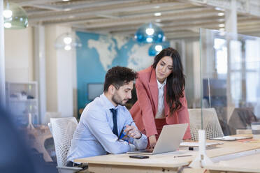 Männliche und weibliche Unternehmer besprechen einen Geschäftsplan auf einem Laptop in einem Coworking-Büro - EIF00968