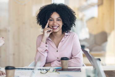 Lächelnde Geschäftsfrau mit wiederverwendbarem Kaffeebecher im Büro - JSRF01517