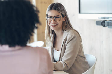 Smiling female professional with coworker in office - JSRF01525