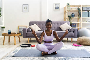 Lächelnde junge Frau, die zu Hause Yoga übt - GIOF12580