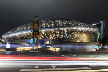 South Korea - JUNE 28, 2018:Glowing Dongdaemun Design Plaza with bronze figure landmarks in central district of Seoul and popular tourist destinations - ADSF23791