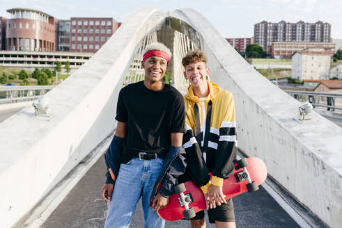 Zwei gut aussehende Teenager mit Skateboard stehen auf der Brücke - ADSF23817