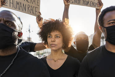 Crop anonymous African American social justice warriors in masks during BLM manifestation in city in back lit - ADSF23908