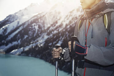 Woman with hiking poles by standing by mountain - AZF00316