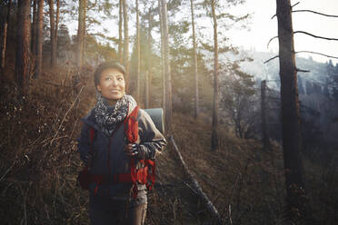 Mittlere erwachsene Frau lächelt beim Wandern im Wald - AZF00323