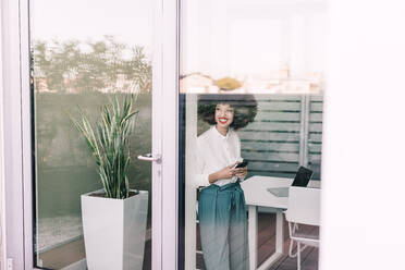 Geschäftsfrau, lächelnd, schaut durch ein Fenster - ISF24392