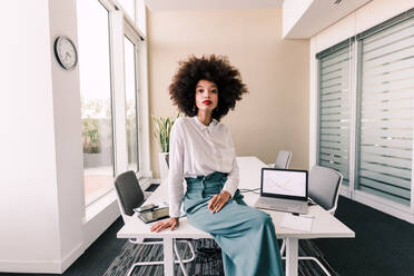 Portrait of businesswoman sitting on desk in office - ISF24407