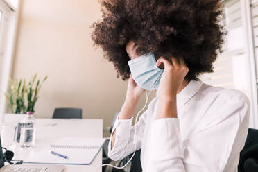 Businesswoman putting on face mask - ISF24414