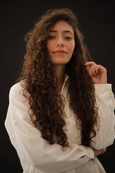 Studio portrait of young woman with long curly hair - ISF24451