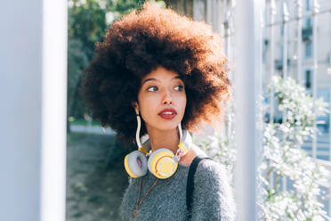 Young woman outdoors, looking away, wearing headphones - ISF24457