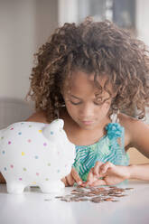 Girl with piggy bank counting coins - ISF24496