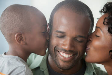 Boy and woman kissing man on cheeks - ISF24525