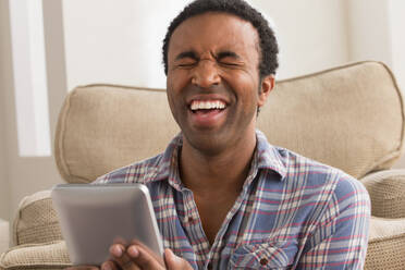 Young man with electronic book, laughing - ISF24540