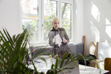 Woman cleaning protective screen partition around desk - ISF24571