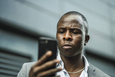 Seriöser schwarzer männlicher Chef, der in der Stadt ein Mobiltelefon durchsucht - ADSF24045