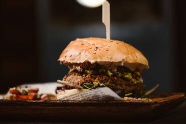 Low Winkel der leckeren Burger mit vegetarischen Patty und gegrillten Shiitakes zwischen Brötchen in der Nähe von Süßkartoffel und Karottenscheiben mit Alioli-Sauce auf dunklem Hintergrund - ADSF24052