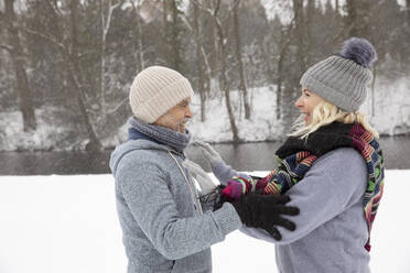 Smiling senior couple touching while standing at park during winter - FVDF00138