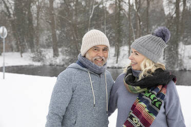 Couple smiling while standing at park during winter - FVDF00141