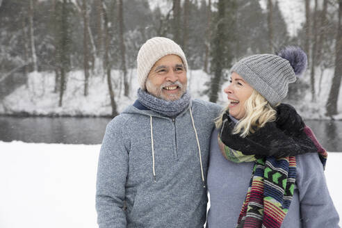 Fröhliche Frau sieht lächelnden Mann im Park im Winter an - FVDF00143