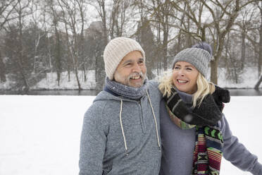 Senior couple wearing warm clothing smiling at park - FVDF00145