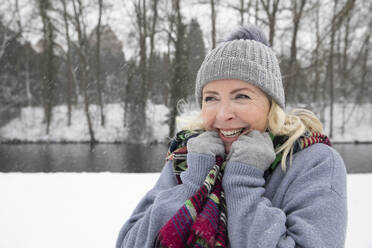 Fröhliche Frau in warmer Kleidung im Park im Winter - FVDF00151