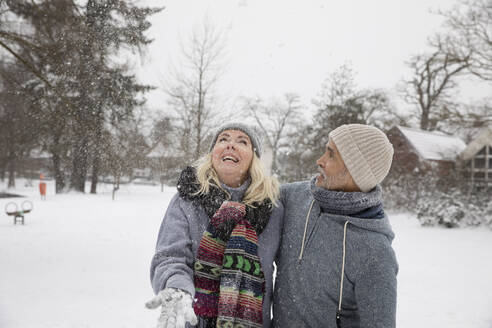 Glückliche Frau, die mit Schnee spielt, während sie im Park steht - FVDF00154
