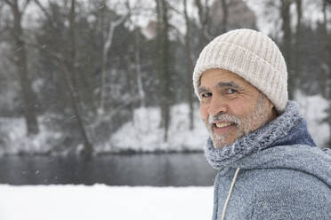 Smiling man wearing knit hat at park - FVDF00157