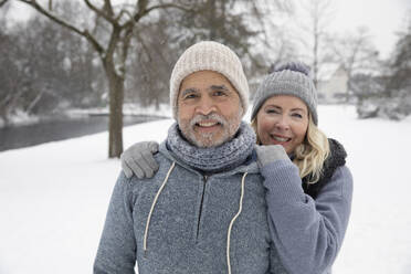 Smiling woman in warm clothing standing with man at park - FVDF00164