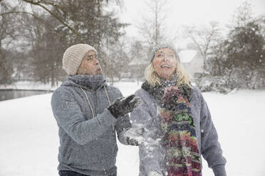 Senior couple throwing snow while playing during winter - FVDF00169