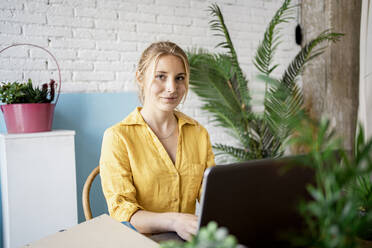Weibliche Fachkraft mit Laptop im Büro zu Hause sitzend - RCPF01018