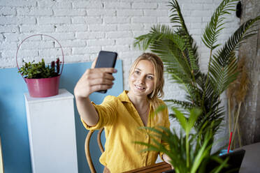 Geschäftsfrau nimmt Selfie durch Smartphone im Büro zu Hause - RCPF01027