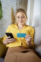 Berufstätige Frau mit Brille beim Online-Shopping zu Hause - RCPF01036