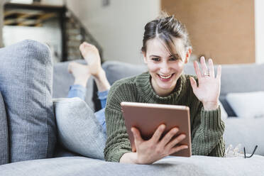 Young woman waving during video call on digital tablet at home - MCVF00785