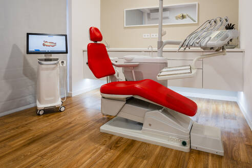 Flachbildschirm hinter einem leeren Zahnarztstuhl in einer Klinik - DLTSF01847