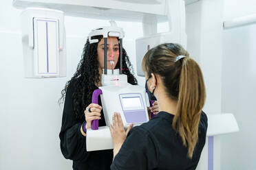 Female dentist operating machine during medical examination of young patient at clinic - DLTSF01867