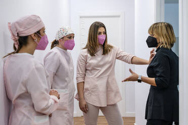 Female dentist gesturing while talking with colleagues in clinic - DLTSF01877
