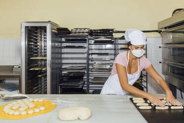 Frau rollt Teig auf einem Tisch in einer Bäckerei - JRVF00517