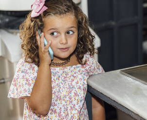 Nettes Mädchen spricht in einer Bäckerei mit ihrem Handy - JRVF00532