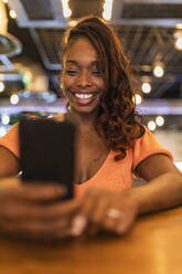 Frau mit Mobiltelefon an der Bar - JRVF00545