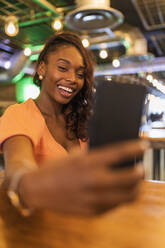 Lächelnde Frau, die ein Selfie mit ihrem Smartphone in einer Bar macht - JRVF00547