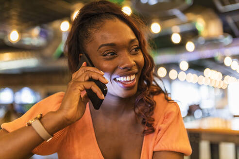 Frau schaut weg, während sie in einer Bar mit ihrem Smartphone telefoniert - JRVF00548