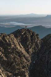 Man with arms outstretched standing on mountain peak - RSGF00675