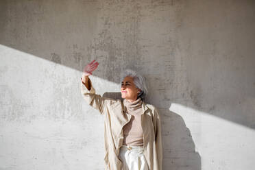 Woman looking away while standing in front of wall during sunny day - ASSF00006