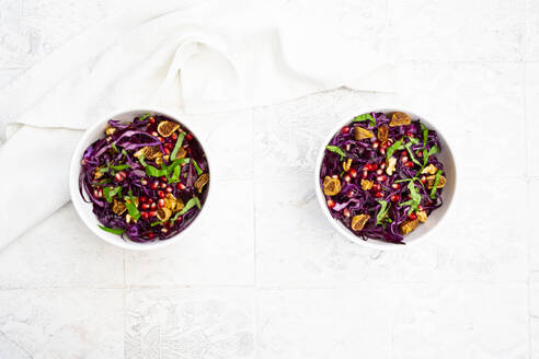 Zwei Schalen veganer Salat mit Rotkohl, Granatapfelkernen, getrockneten Feigen, Walnüssen und Basilikum - LVF09155
